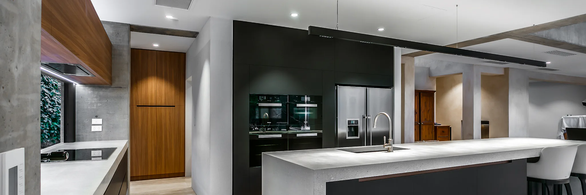 Black panelled kitchen with concrete island and benchtops Black panelled kitchen with concrete island and benchtops