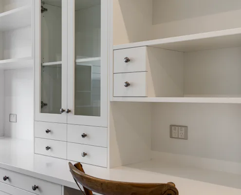 Customised study storage & work area Close up of white custom made joinery in study room, with drawers, open shelving and work space