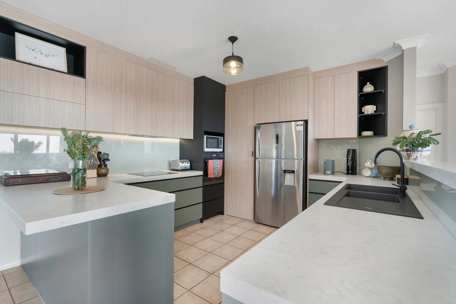 Renovated kitchen with stone countertops, wood effect upper cabinets and green lower cabinets
