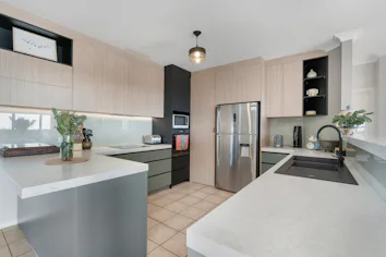 Renovated kitchen with stone countertops, wood effect upper cabinets and green lower cabinets